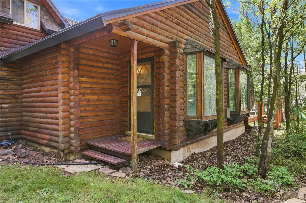 Log cabin exterior with exposed wood siding, a covered entry, and multiple bay windows
