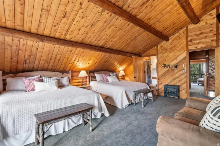 Vaulted wood-paneled ceiling with exposed beams, wood-planked walls, and carpet flooring