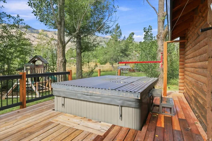 Wood plank deck featuring an integrated hot tub and natural wood log siding