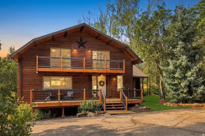 Log-style exterior with wood siding, dual-level balconies, prominent gabled roofline, and a multi-pane front door