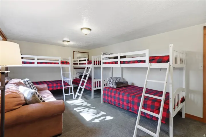 Carpeted room featuring multiple white bunk beds and a built-in light fixture