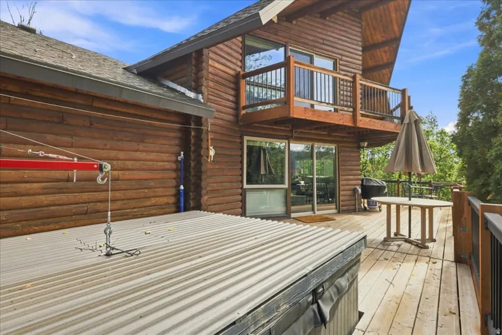 Wood-sided exterior featuring an upper-level balcony, a large deck, and expansive glass sliding doors