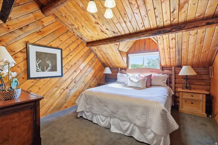 Wood-paneled sloped ceiling, exposed wood beams, and a window with a wood frame