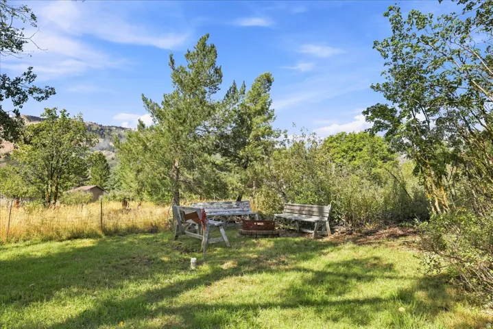 Grassed outdoor space featuring a fire pit area with rustic benches