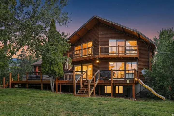 Log cabin exterior with multiple balconies, a spacious wood deck, and a multi-level wooden staircase