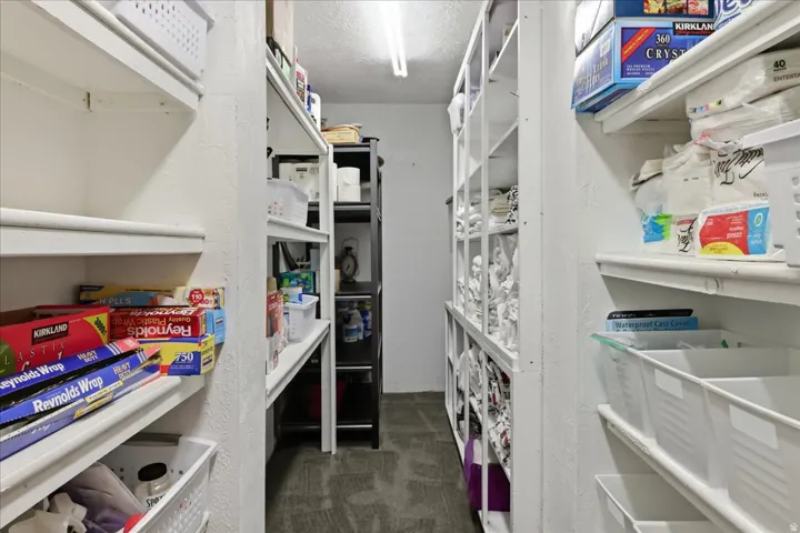 Extensive pantry with multiple white built-in shelves and a recessed ceiling light fixture