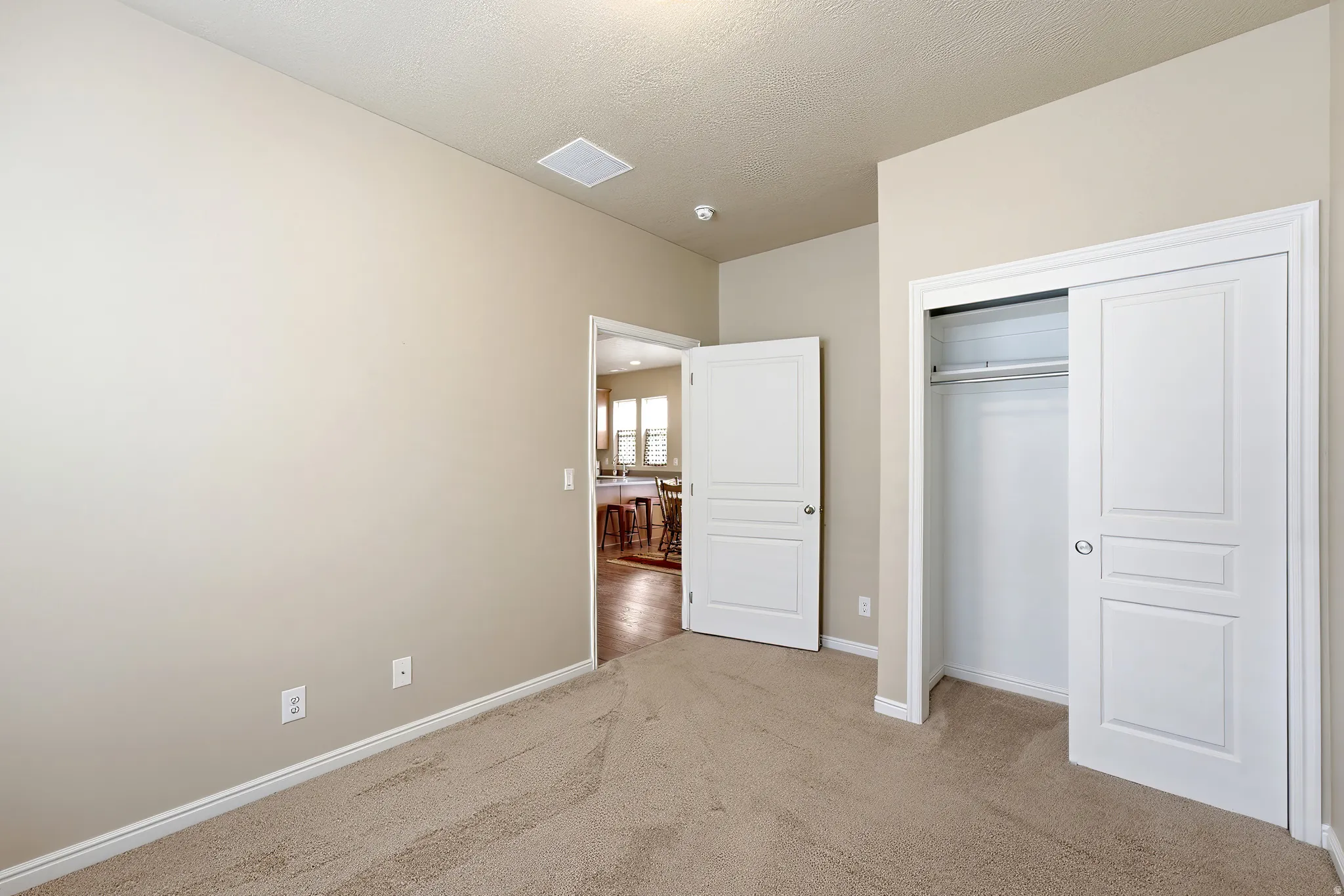 Light-toned carpeting, neutral wall color, white trim, and a bi-fold closet with panel details
