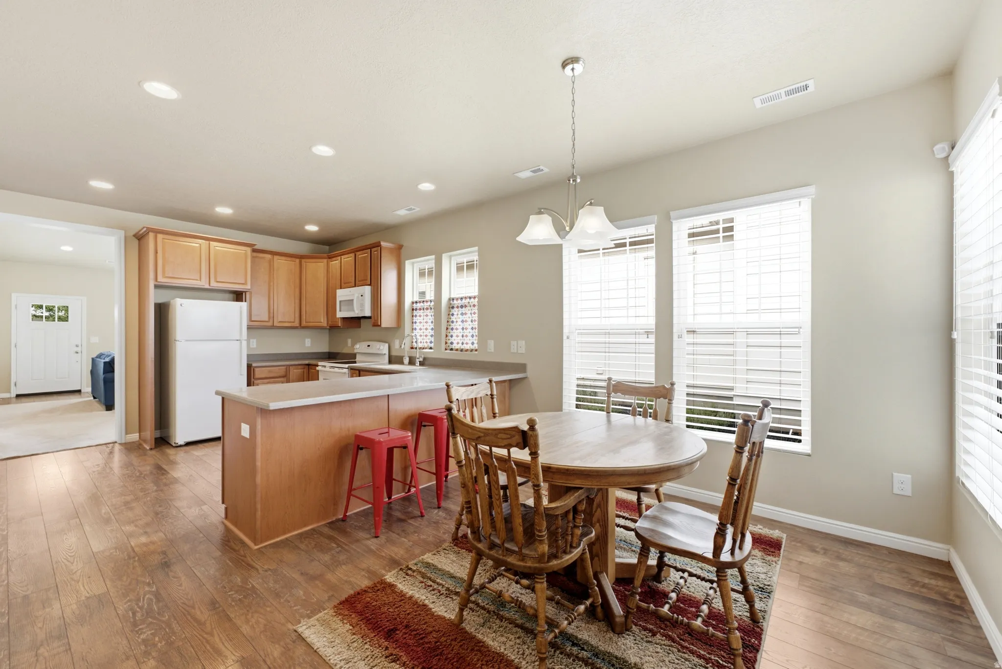Open-concept kitchen featuring wood-finish flooring, recessed lighting, wood cabinetry, and a kitchen island with a breakfast bar
