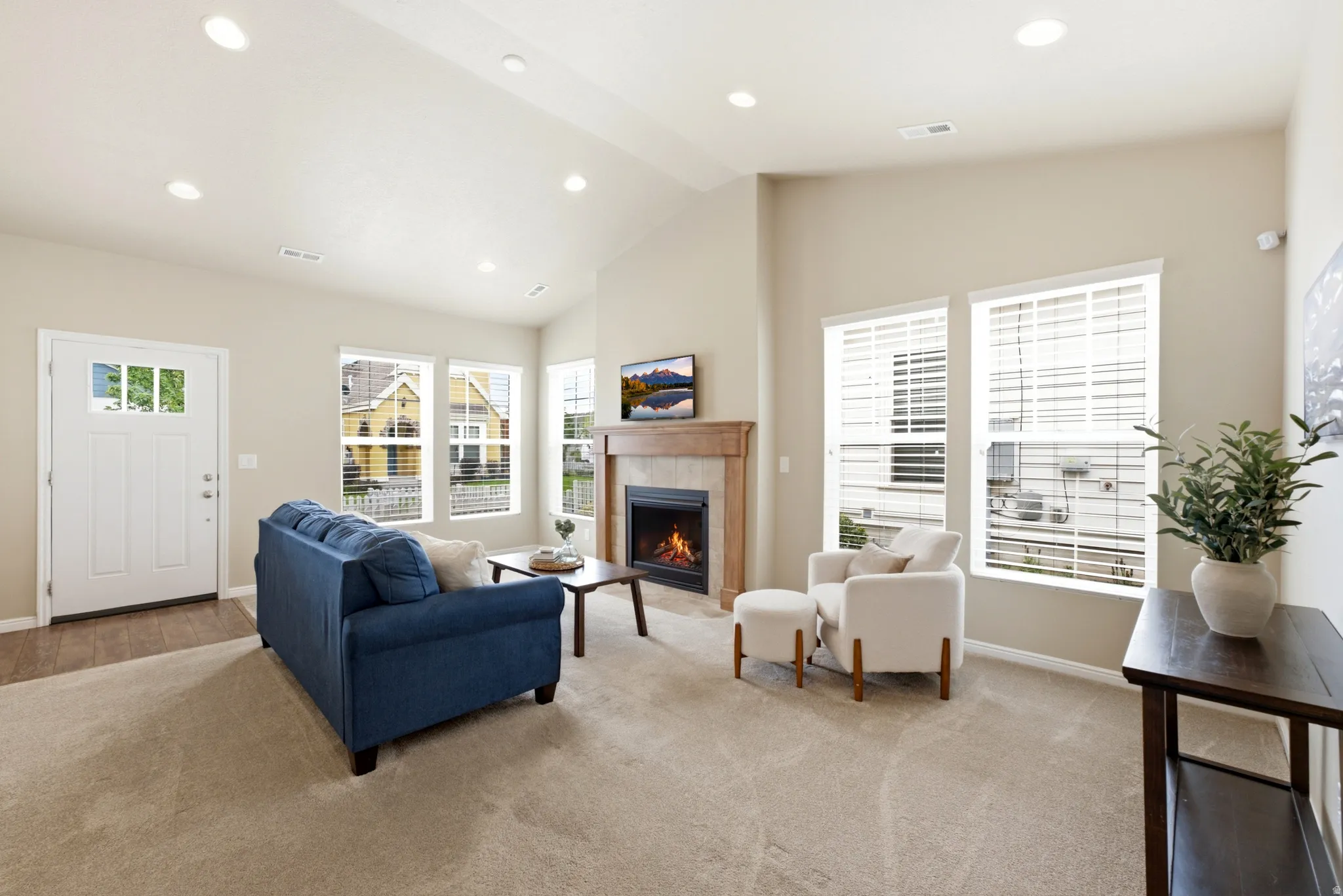 Vaulted ceiling, recessed lighting, wood-finish flooring, fireplace with wood mantel, multiple windows with blinds