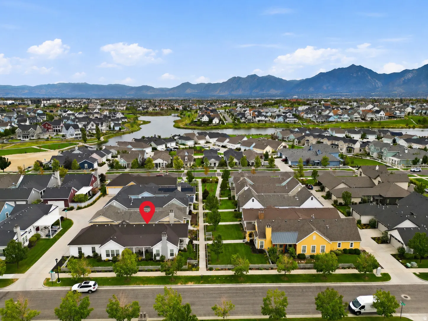 Aerial perspective of a residential neighborhood with a prominent lake and distant mountains