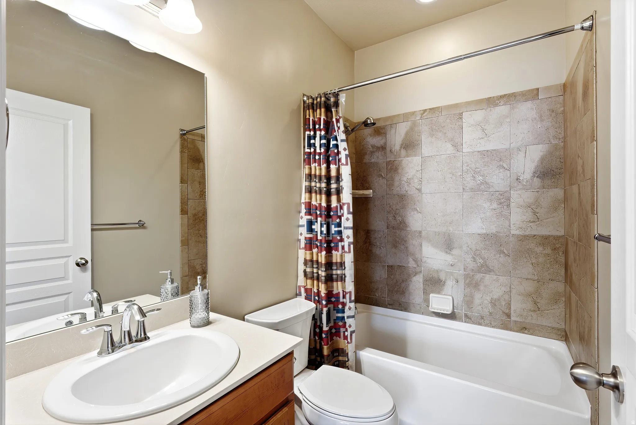 Vanity with integral sink, chrome faucet, wood-finish cabinetry, and a full-width mirror