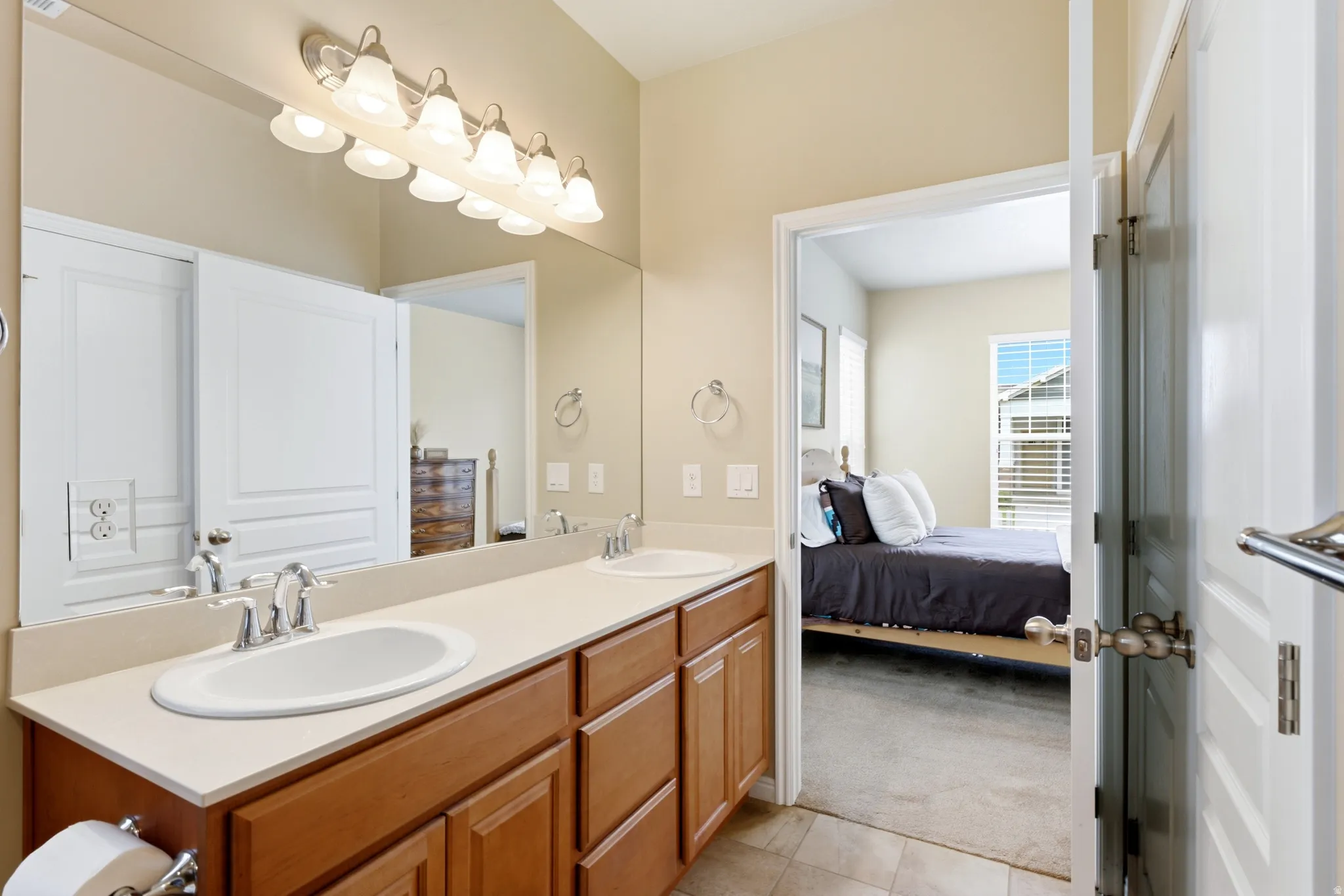Bathroom vanity with dual undermount sinks, chrome fixtures, and a large wall-mounted mirror