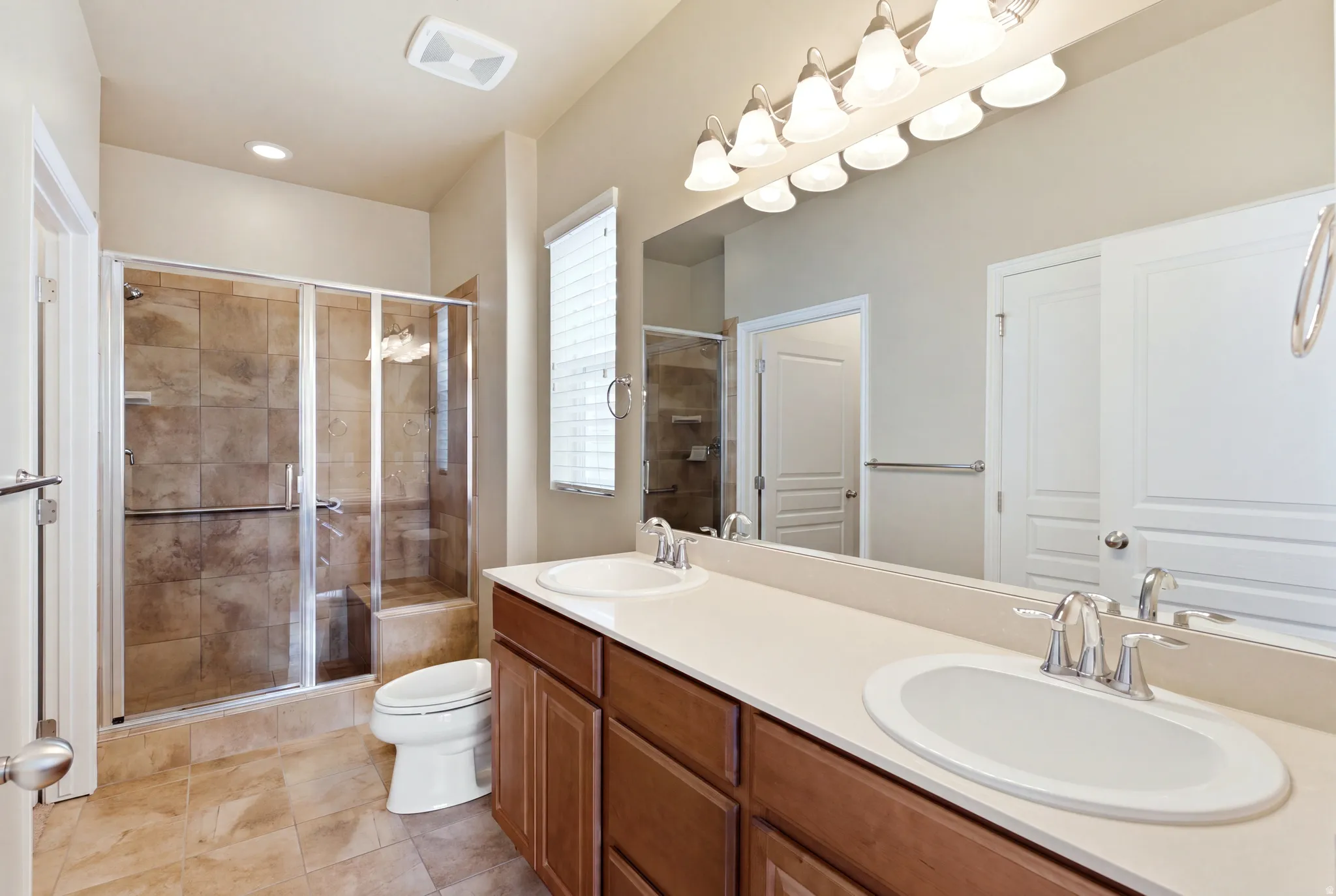 Dual vanity with undermount sinks, expansive mirror, and tile flooring