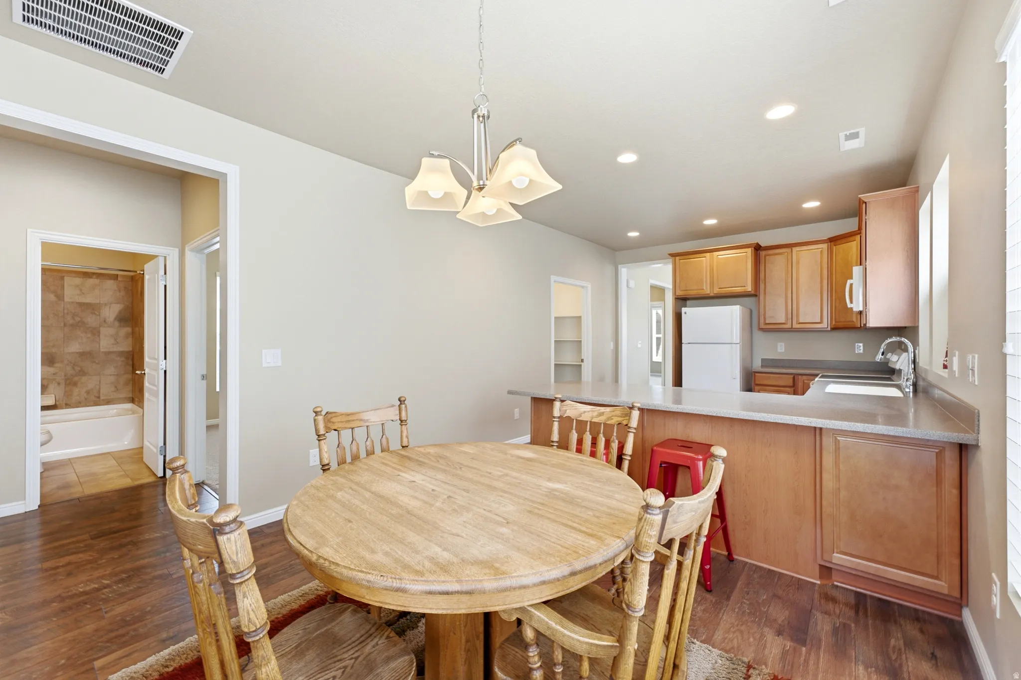 Open-concept living space featuring wood-finish flooring, recessed lighting, and a kitchen with wood cabinetry and a breakfast bar