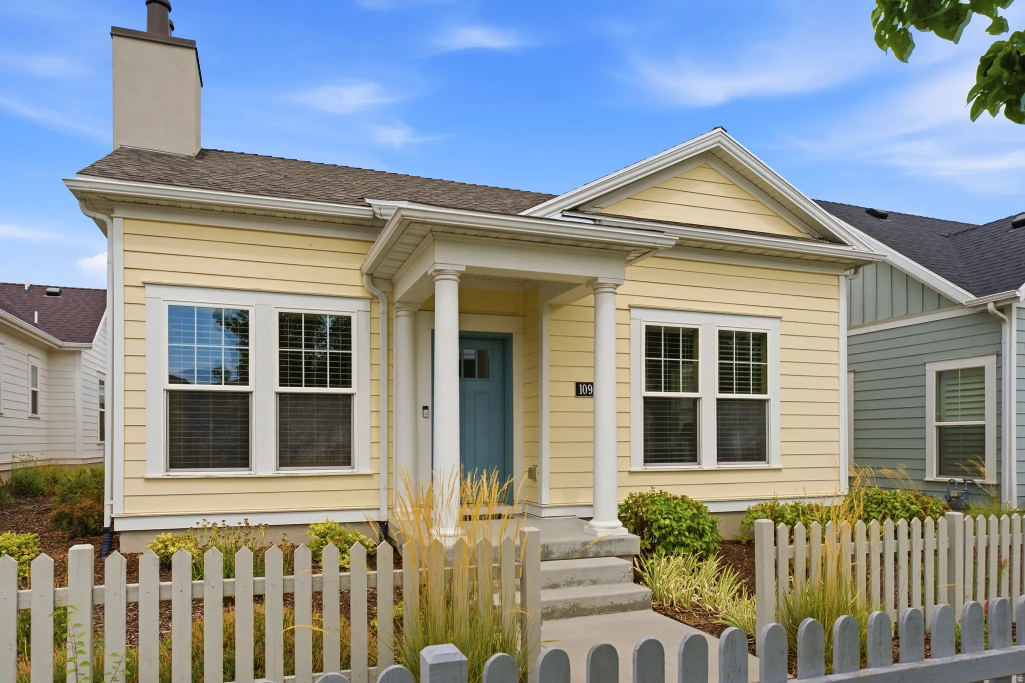 Yellow siding exterior with a pitched roof and a prominent chimney