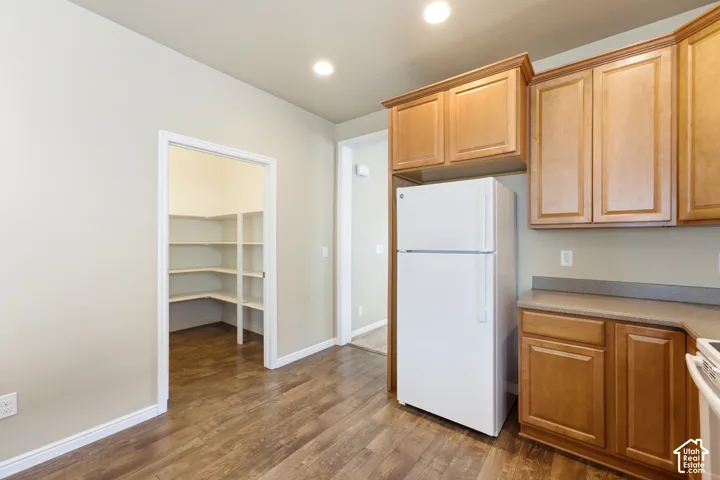 Kitchen featuring wood-finish flooring, recessed lighting, wood cabinetry, stone-look countertops, and a walk-in pantry with built-in shelving
