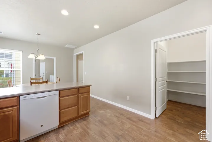 Kitchen island with integrated dishwasher, wood-finish flooring, recessed lighting, and a pantry with built-in shelving
