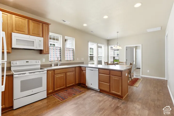 Kitchen featuring wood-finish flooring, recessed lighting, white appliances, and warm wood cabinetry