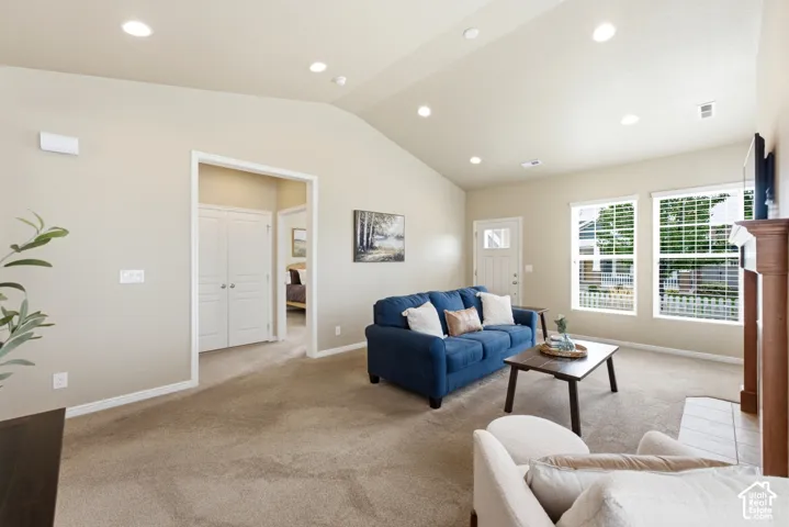 Vaulted ceiling with recessed lighting, carpeted flooring, multiple windows, and a wood-finish mantel