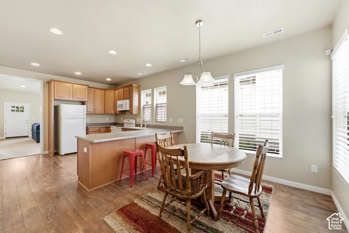 Open-concept kitchen featuring wood-finish flooring, recessed lighting, wood cabinetry, and a kitchen island with a breakfast bar