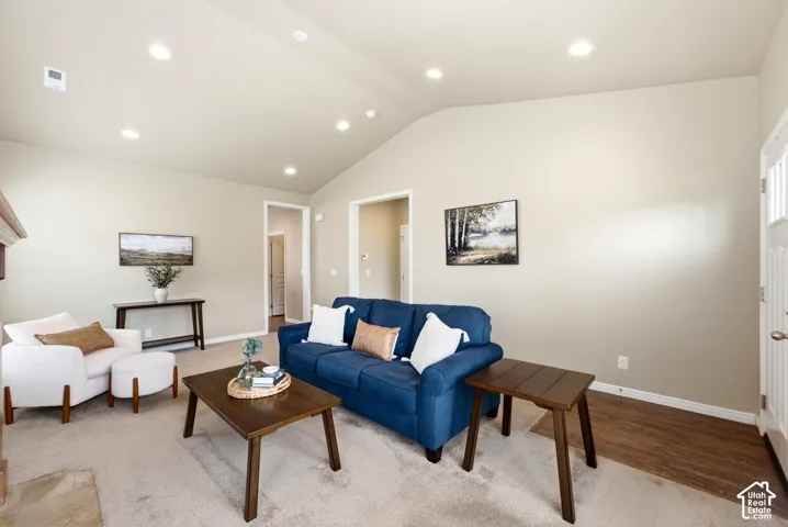Vaulted ceiling with recessed lighting, neutral wall paint, carpeted flooring, wood-finish flooring, and a white paneled door with window inserts