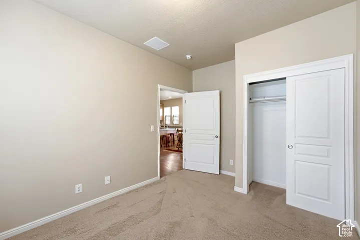 Light-toned carpeting, neutral wall color, white trim, and a bi-fold closet with panel details