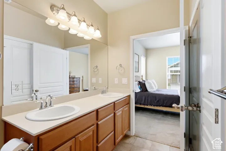 Bathroom vanity with dual undermount sinks, chrome fixtures, and a large wall-mounted mirror