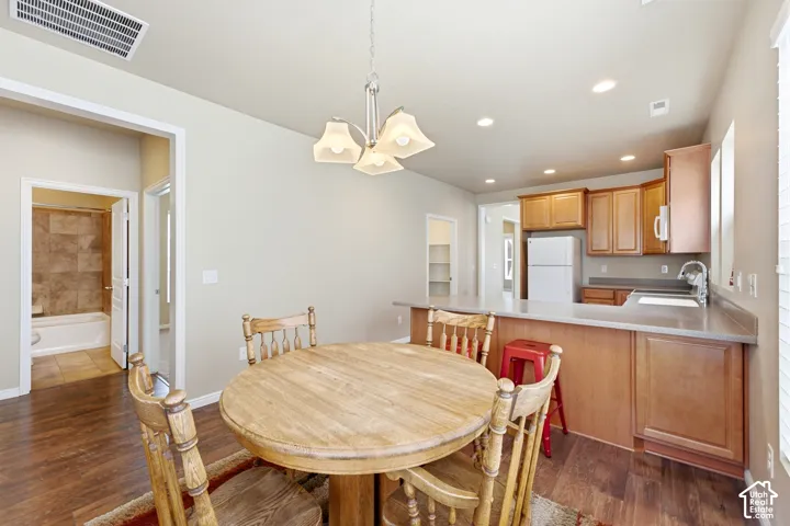 Open-concept living space featuring wood-finish flooring, recessed lighting, and a kitchen with wood cabinetry and a breakfast bar
