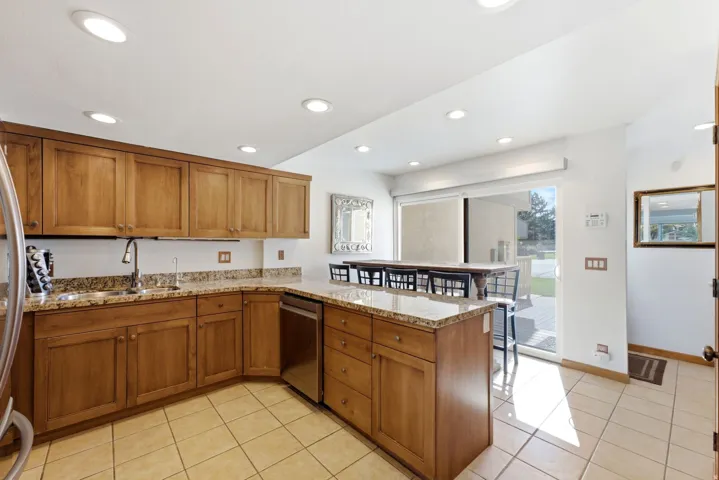 Wood-finish cabinetry with stone countertops, stainless steel appliances, and recessed lighting