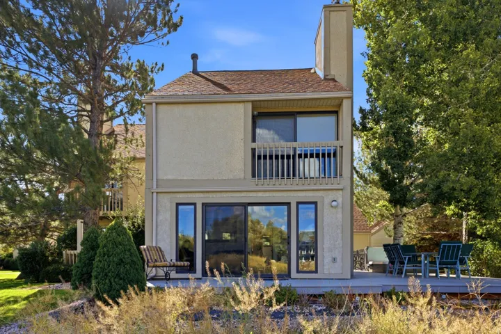 Two-story stucco exterior with a balcony, an upper-level sliding glass door, and a lower-level sliding glass door