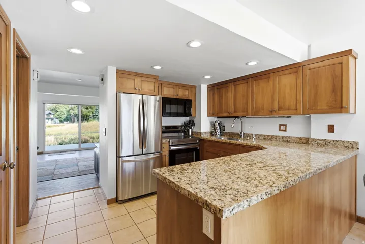Kitchen featuring wood cabinetry, stainless steel appliances, speckled stone countertops, and recessed lighting