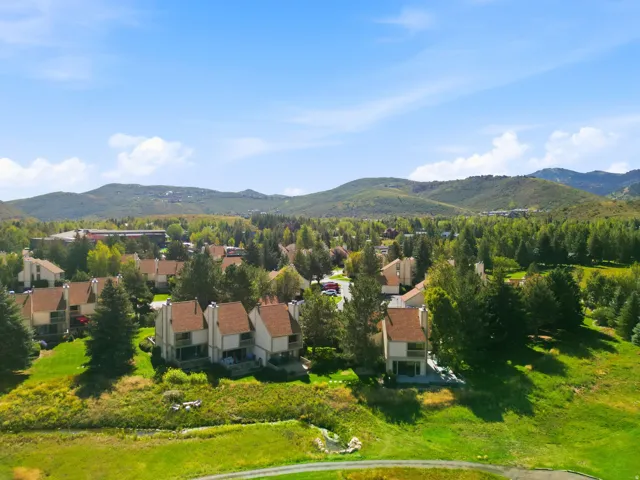 Residential community with multiple structures, expansive green space, mature trees, and mountainous terrain