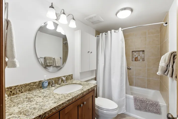 Vanity with a granite countertop, undermount sink, and wood-finish cabinetry