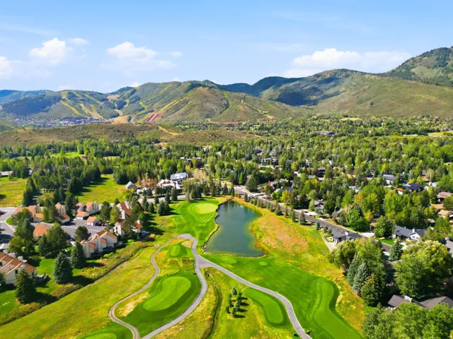 Expansive golf course setting featuring a water hazard, lush green fairways, and paved cart paths