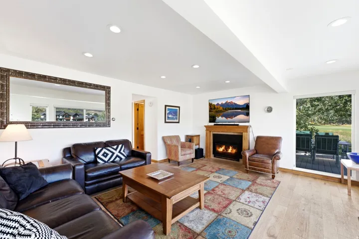 Recessed lighting throughout, wood-finish flooring, built-in fireplace, wood mantle, and sliding glass door to exterior deck