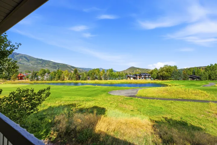 Expansive outdoor area featuring a large pond, verdant landscaping, and distant mountainous terrain