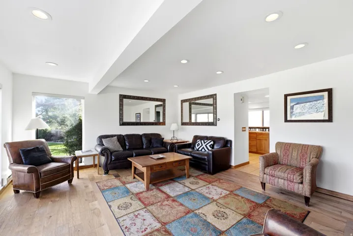 Recessed ceiling lighting, wood-finish flooring, white walls, and a large window