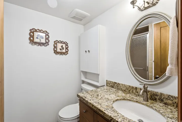 Vanity with an oval undermount sink, granite-style countertop, and brushed nickel faucet