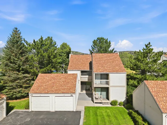 Multi-level structure with a peaked shingle roof, two balconies, and a two-car garage