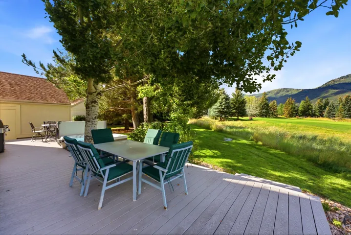 Expansive outdoor deck with composite decking, mature trees, and an open lawn area