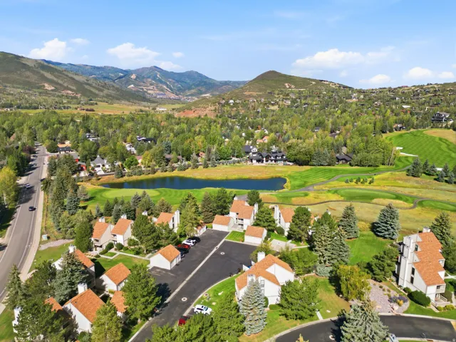 Mountain landscape featuring residential structures, a roadway, a pond, and a golf course