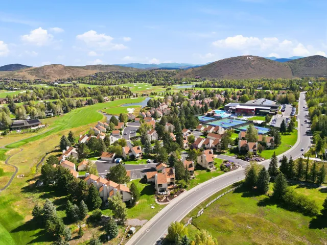 Aerial perspective showcasing the residential community, surrounding green spaces, and distant mountains