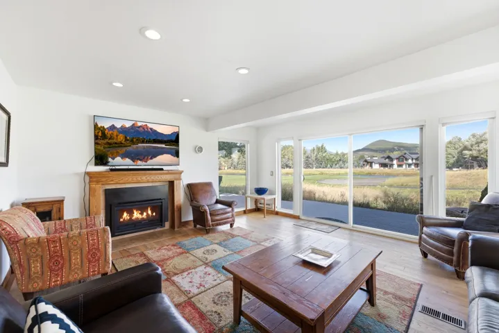Recessed lighting, wood-finish flooring, a built-in fireplace with a wood mantel, and expansive sliding glass doors