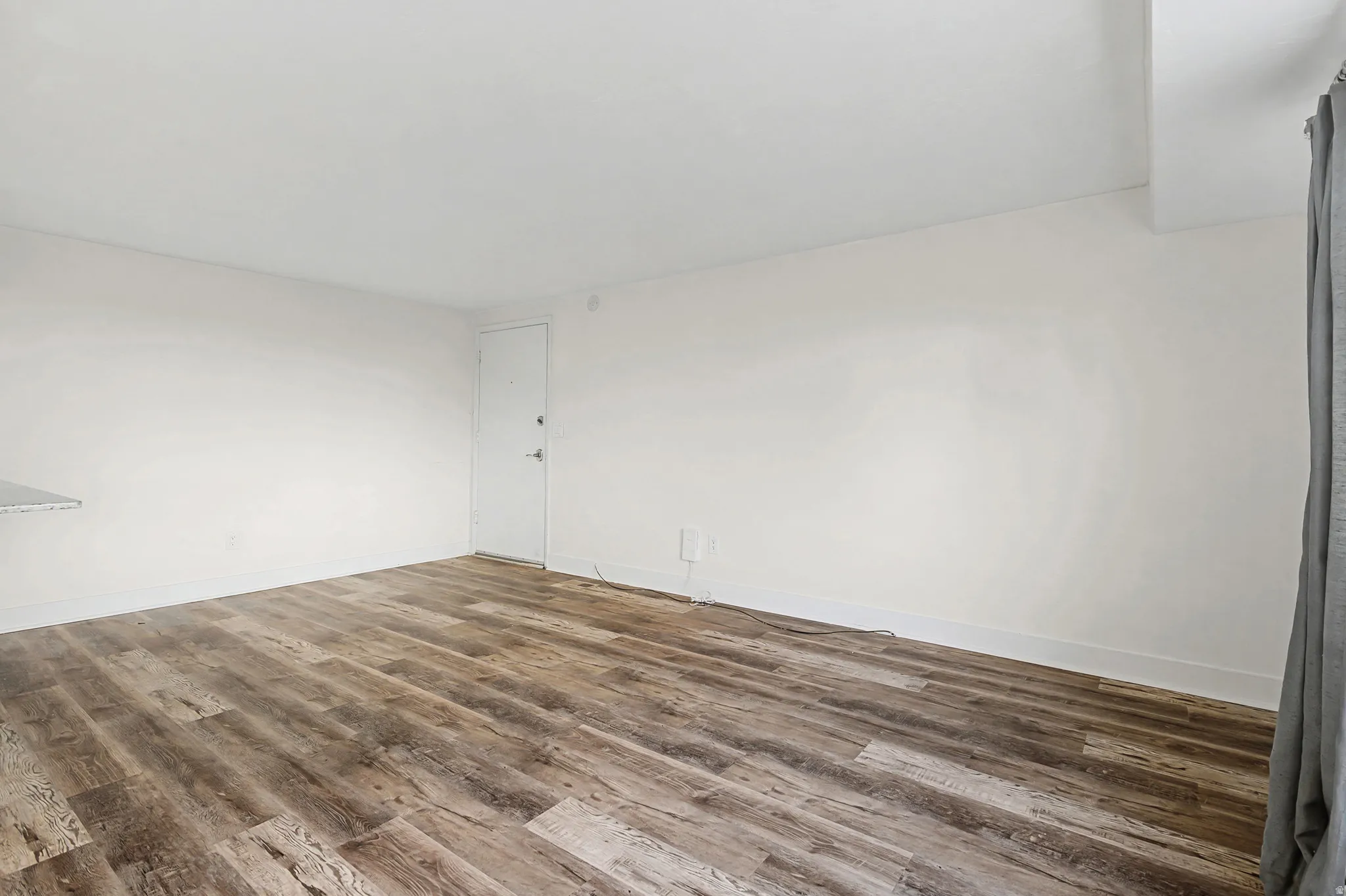 Wood-finish flooring with white walls and a white door
