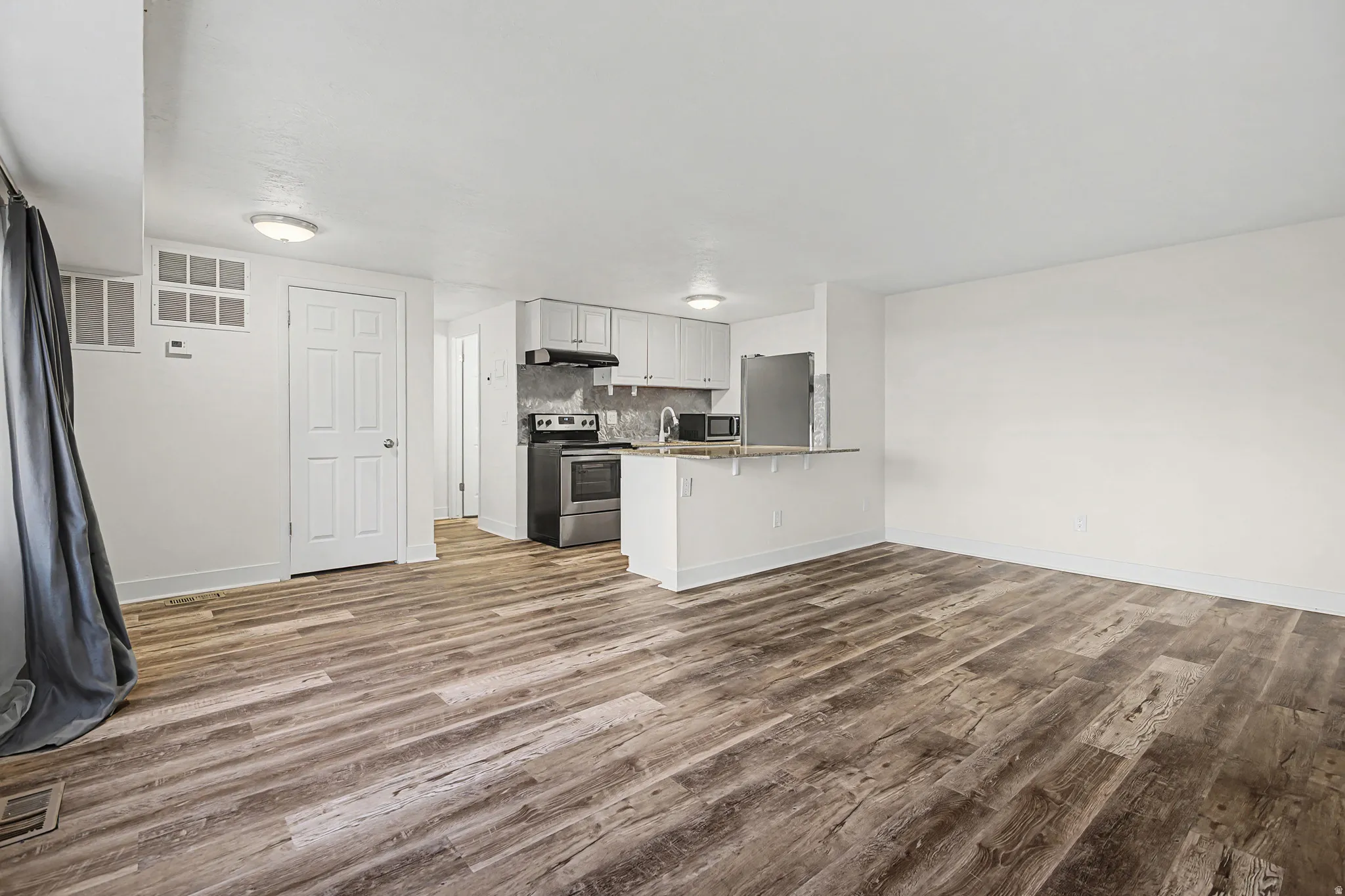 Open-concept living space featuring wood-finish flooring, white walls, and recessed lighting