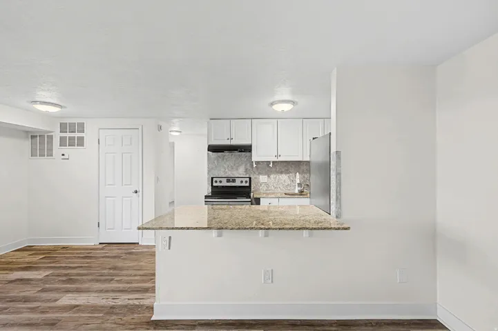 Kitchen featuring white cabinetry, stone-finish backsplash, and stainless steel appliances
