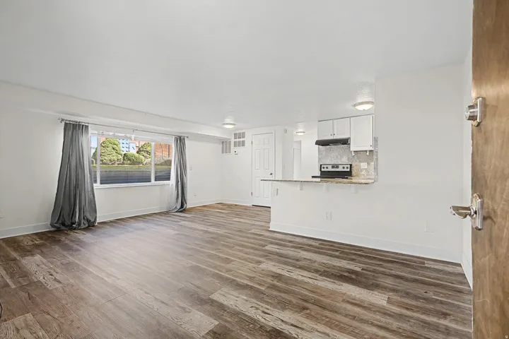 Wood-finish flooring, white cabinetry, integrated range, and a breakfast bar with stone-finish countertop