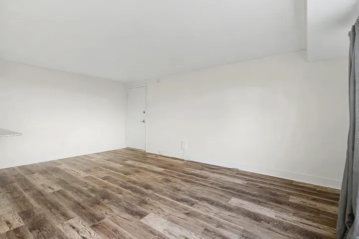 Wood-finish flooring with white walls and a white door