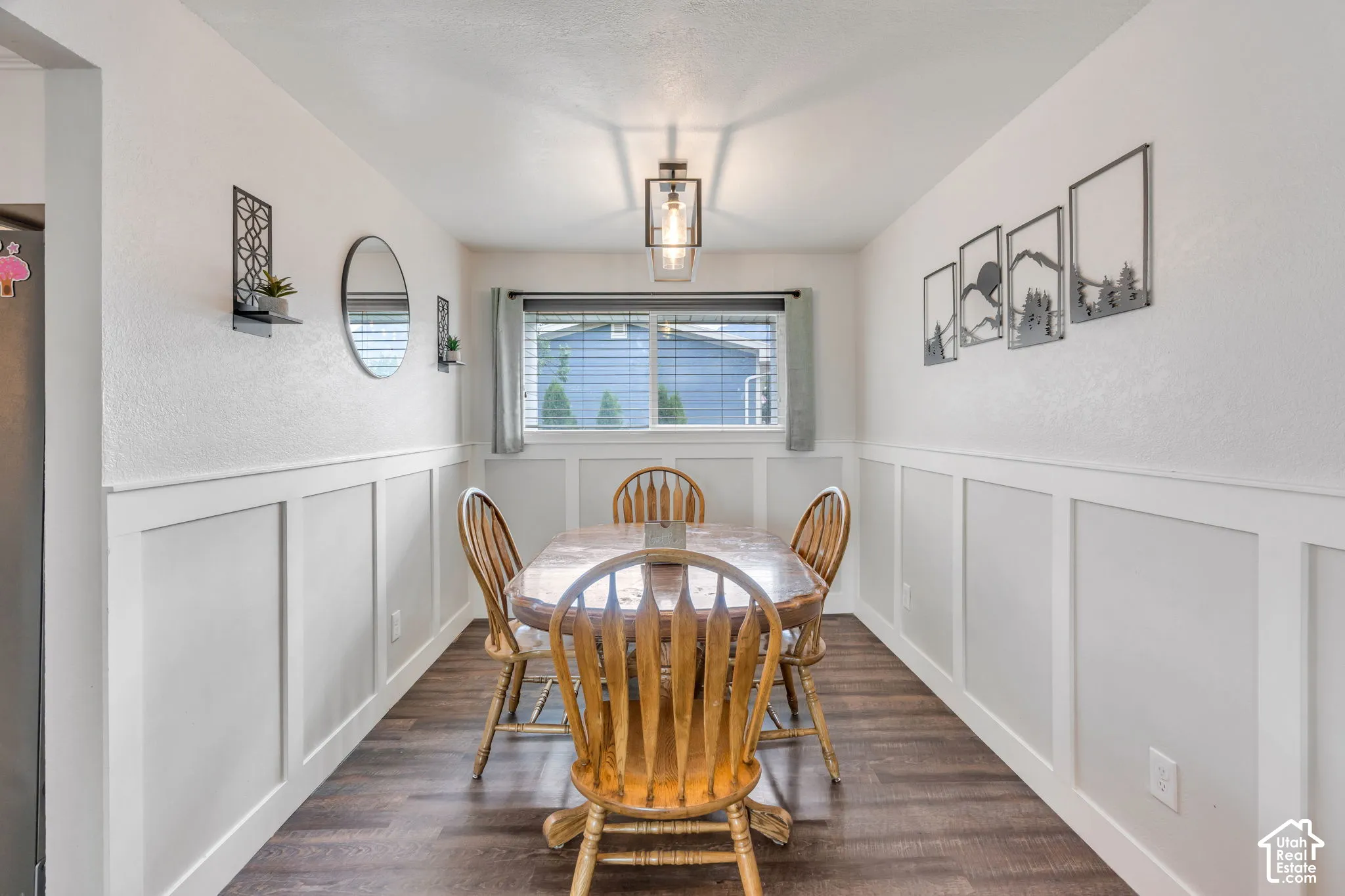 Wood-finish flooring, half-wall wainscoting, and a central window with blinds