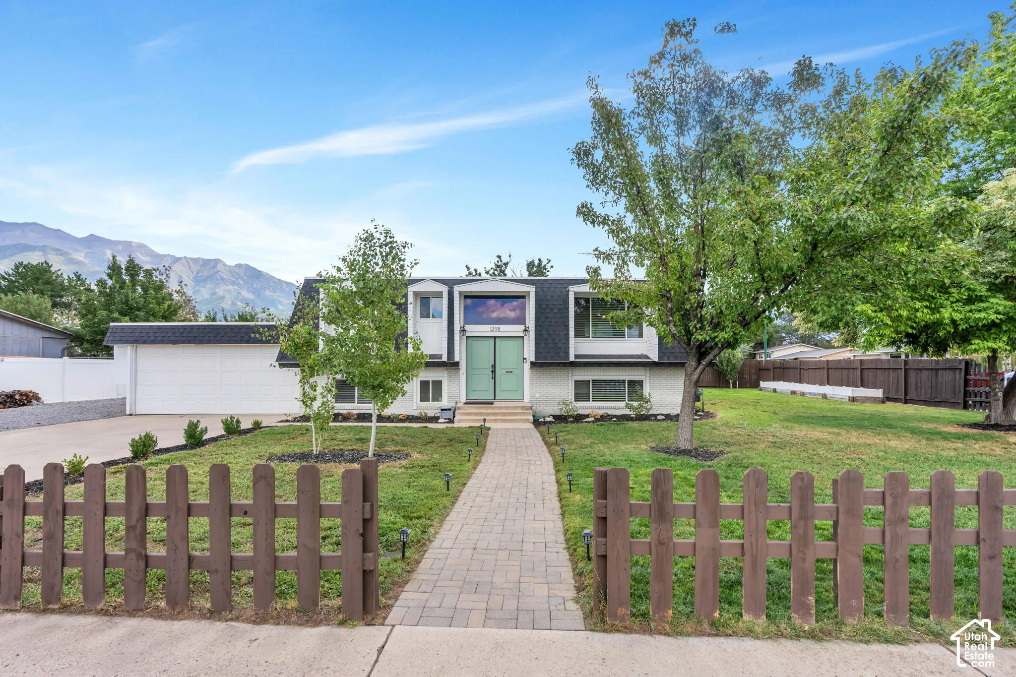 Contemporary architecture with a striking facade, mature trees, a paved walkway, and a garage